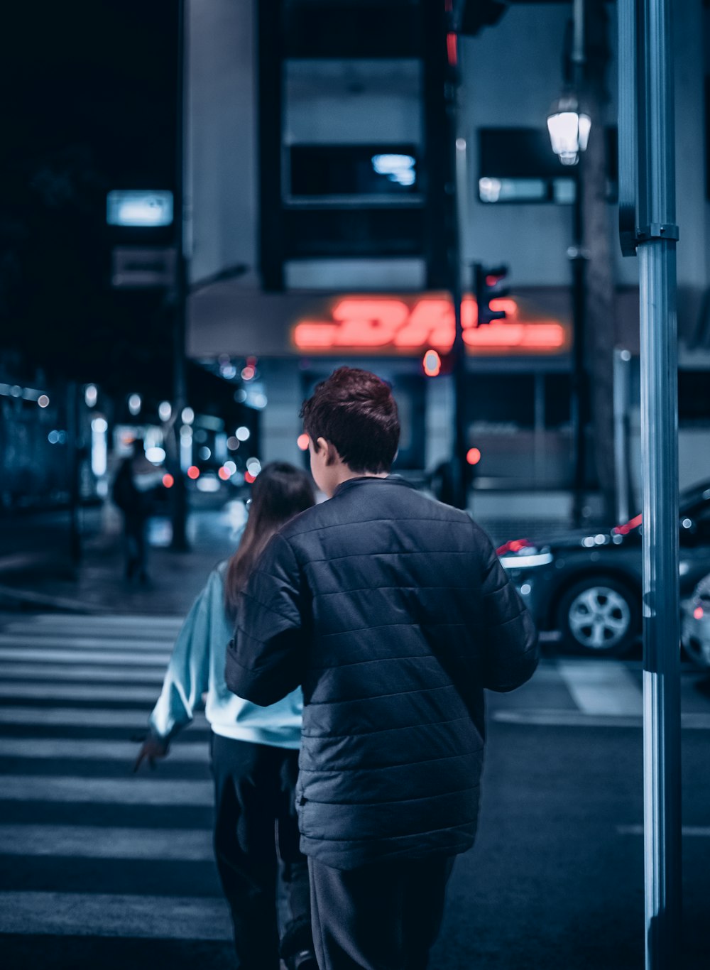 a man and a woman walking down a street at night