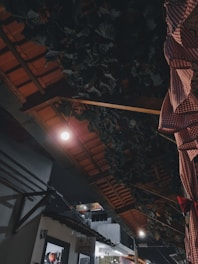 A rooftop corner showcasing elegant pergola shading, cushion-filled benches, and warm hanging lights.