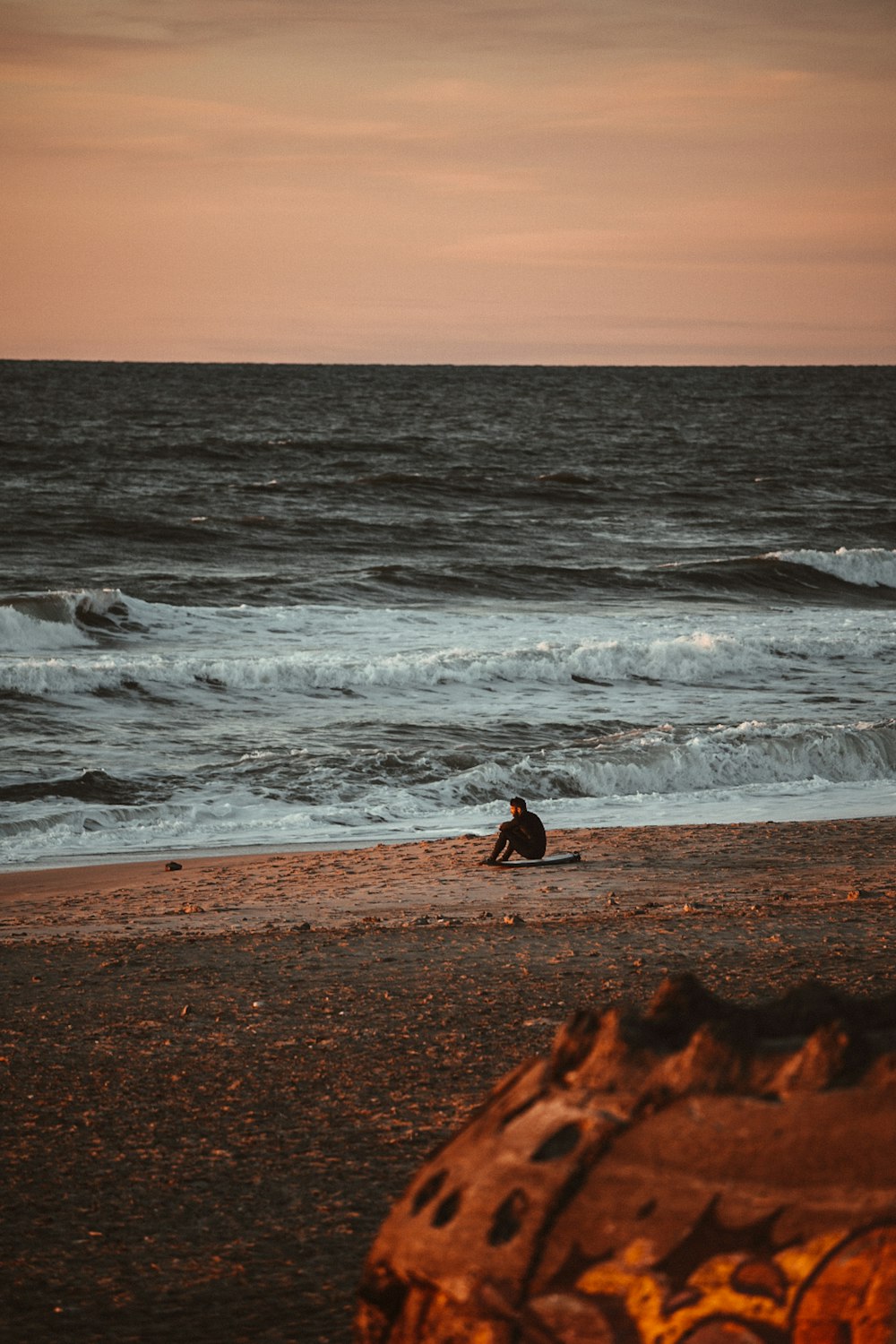 a person sitting on a beach next to the ocean