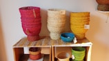 Colorful woven baskets arranged on a rustic wooden shelf.