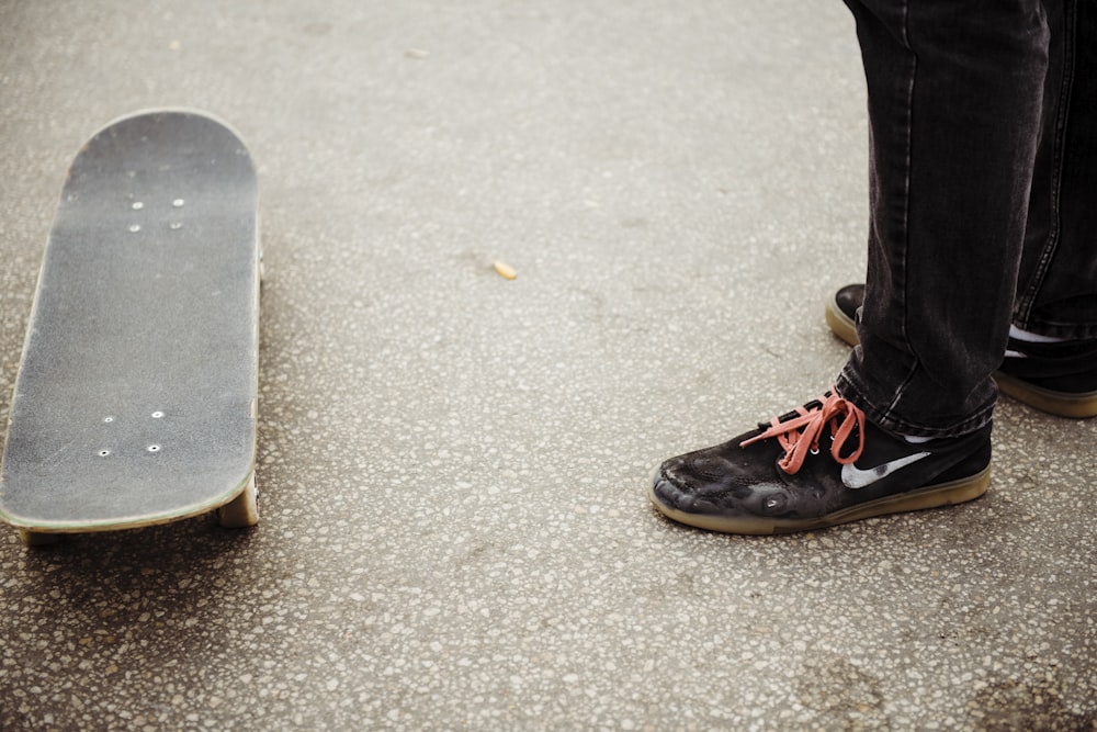 a person standing next to a skateboard on the ground