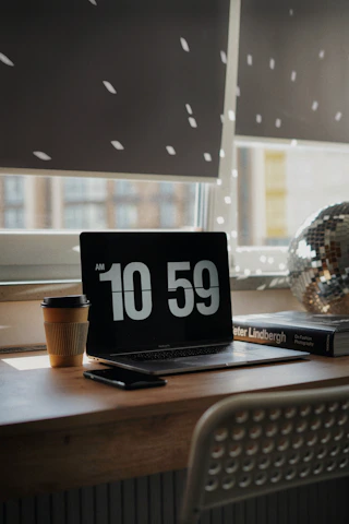 A cozy workspace with travel books, a laptop displaying a travel blog, and a cup of coffee by a window overlooking a sunny street.