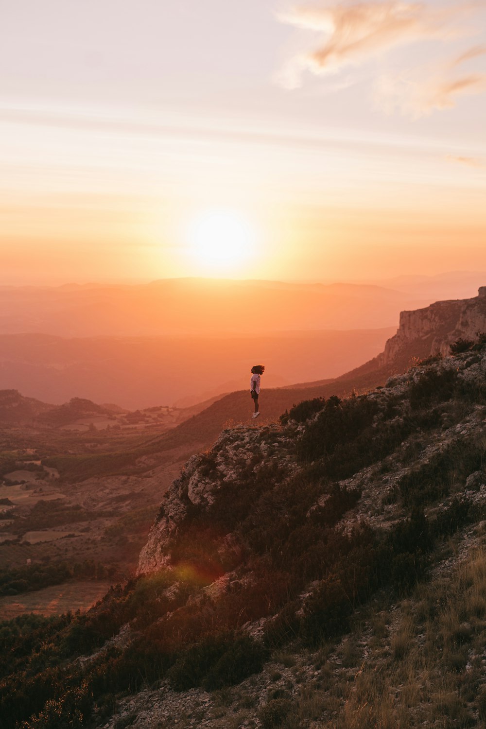 a person standing on top of a hill at sunset