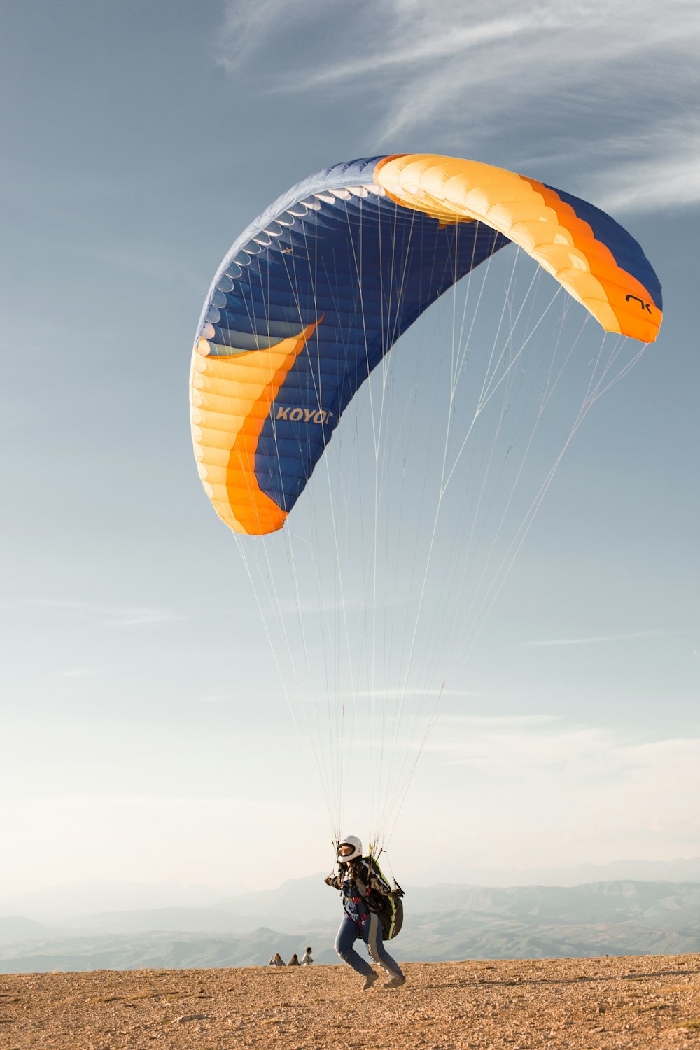 Un uomo che fa volare un grande aquilone blu e arancione