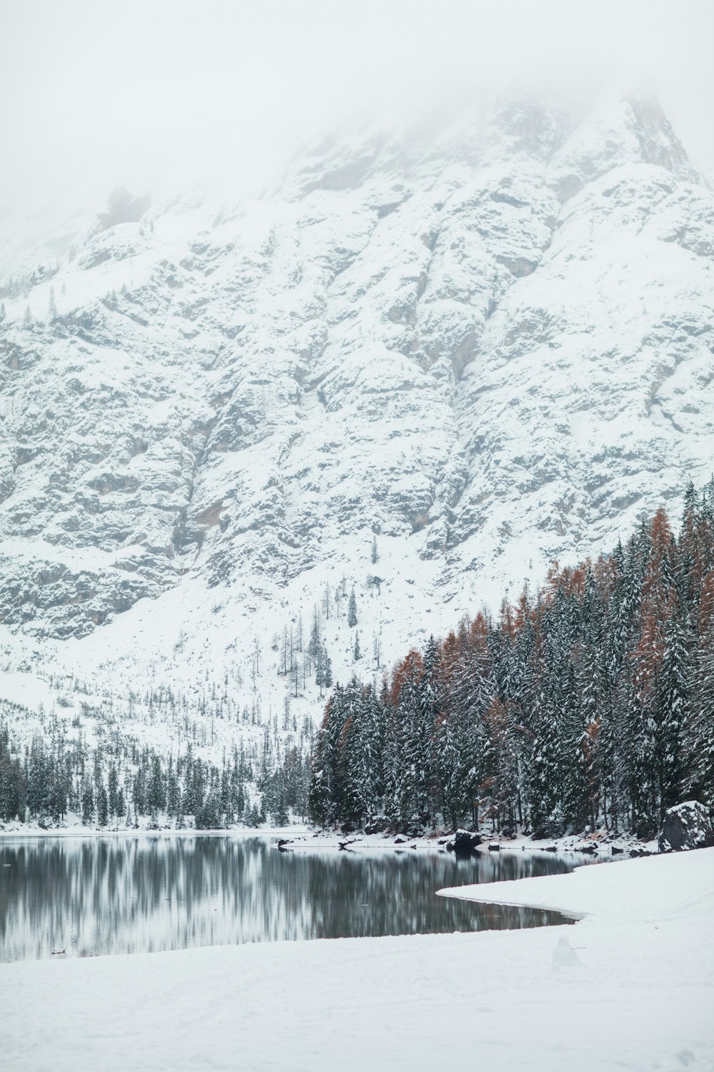 a mountain covered in snow next to a lake