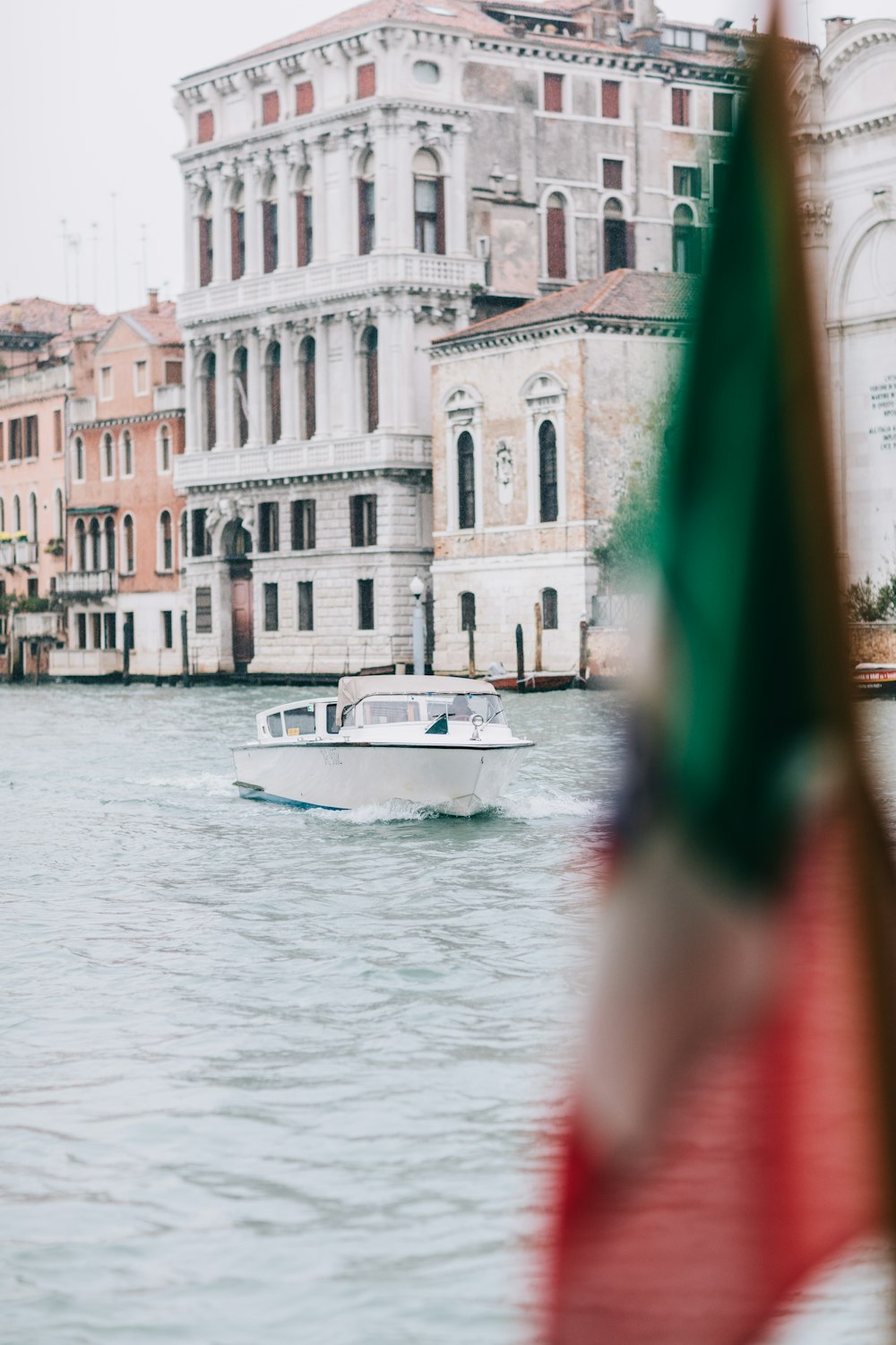 a white boat traveling down a river next to tall buildings