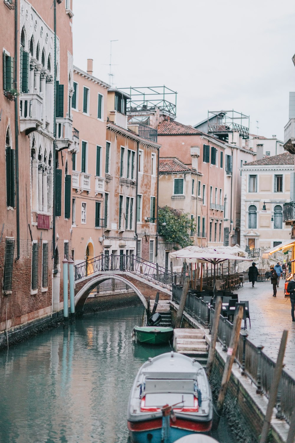 a canal with boats and people walking on it