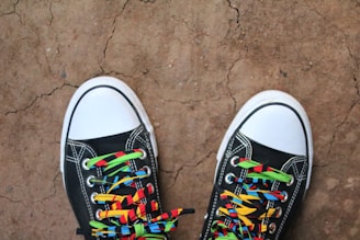 a pair of black shoes with colorful laces on them