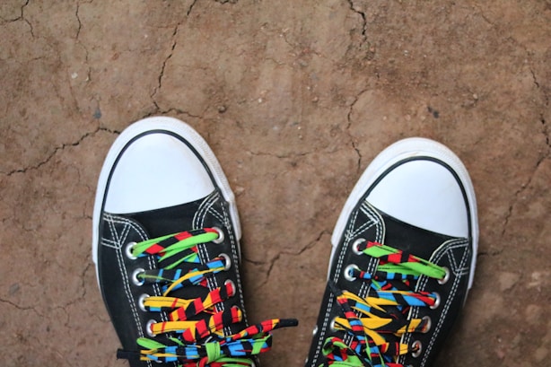 a pair of black shoes with colorful laces on them