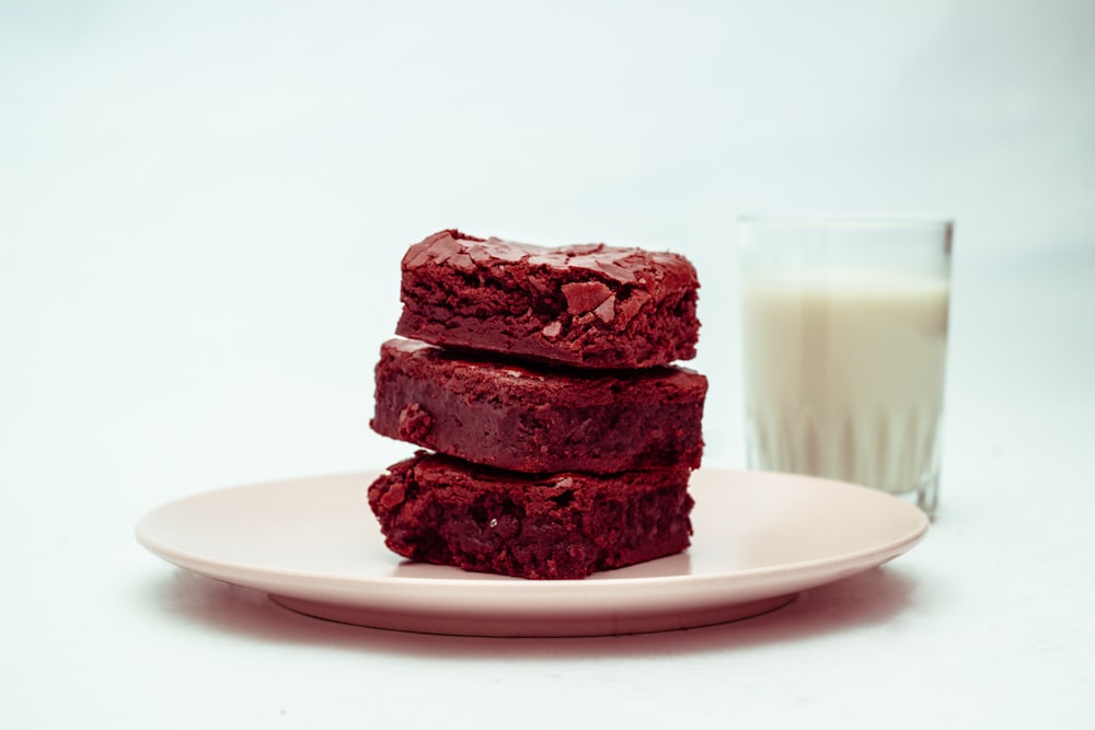 a plate of brownies next to a glass of milk