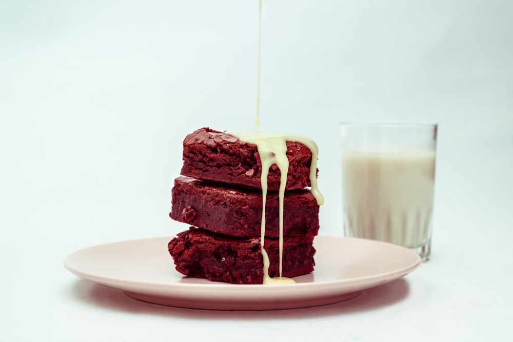 a stack of brownies on a plate next to a glass of milk