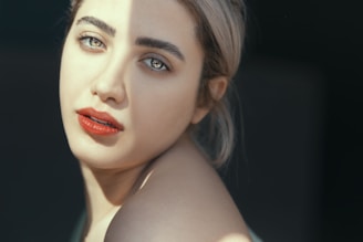 A close-up portrait of a transgender American smiling softly, sunlight casting gentle shadows on their face.