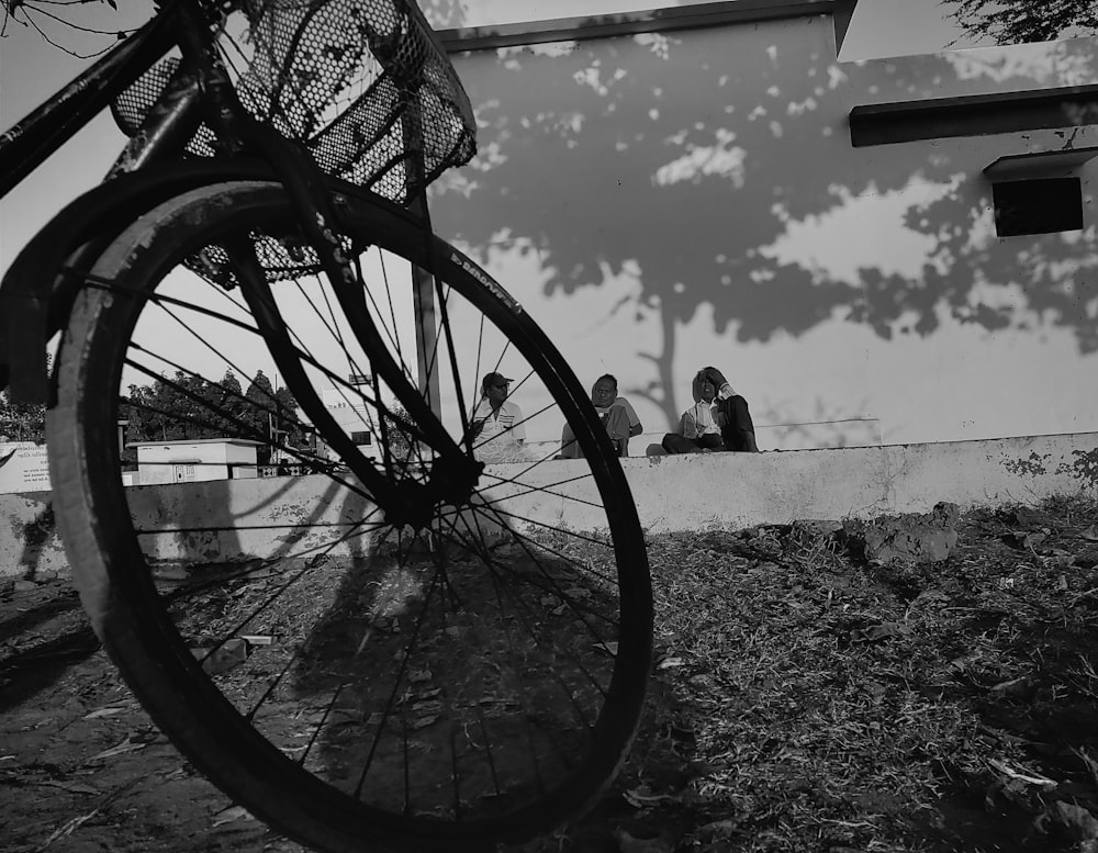 a bicycle parked next to a building with people sitting on it