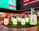 A colorful display featuring cartoonish animal figurines and signs with English and Chinese characters representing different animals of the Chinese zodiac, such as the rat, ox, and rabbit. The figures are placed on illuminated pedestals surrounded by artificial grass, set against the backdrop of a well-lit urban environment with restaurant signage in the background.