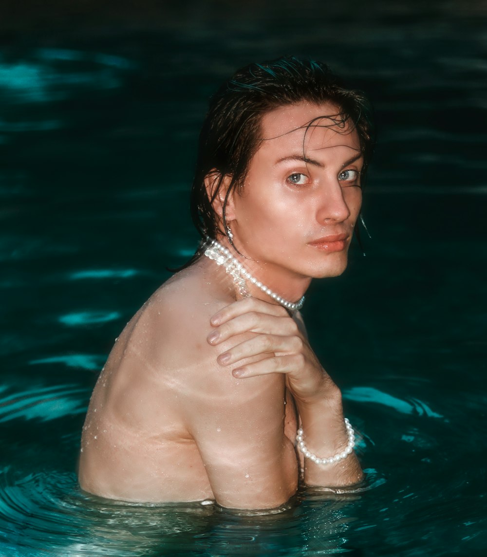 a man in a pool with a pearl necklace around his neck
