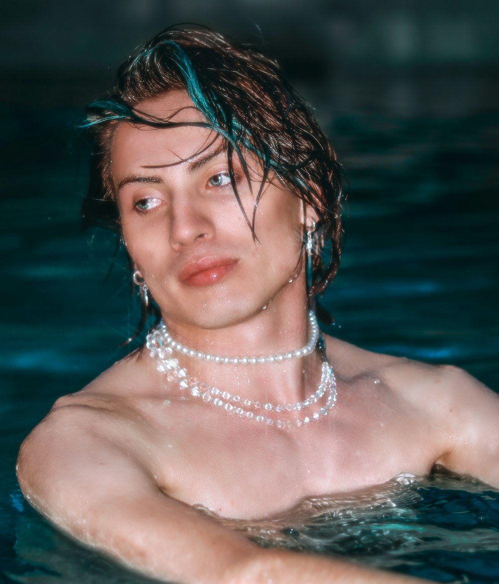 a man wearing a pearl necklace in a pool