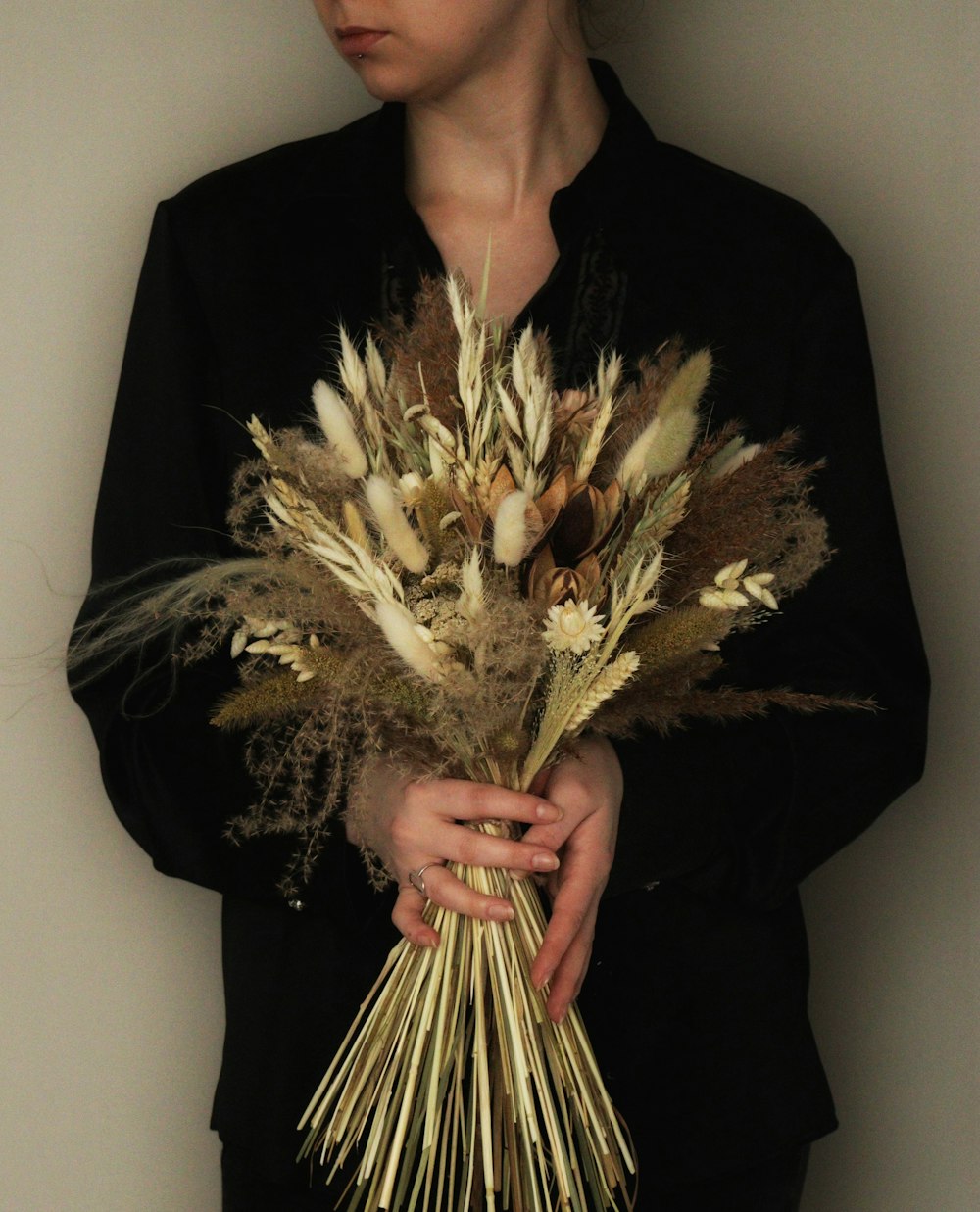 a woman holding a bouquet of dried flowers