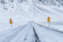 a snow covered road with warning signs on it