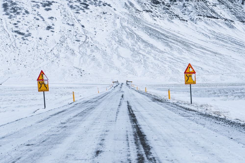 a snow covered road with warning signs on it
