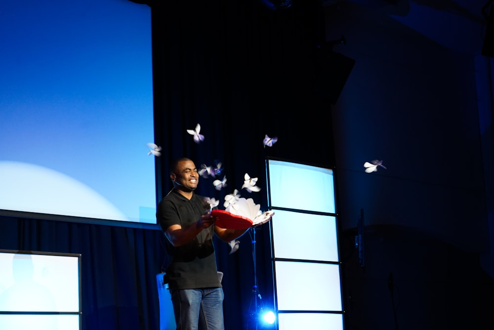 a man standing on a stage holding a red book