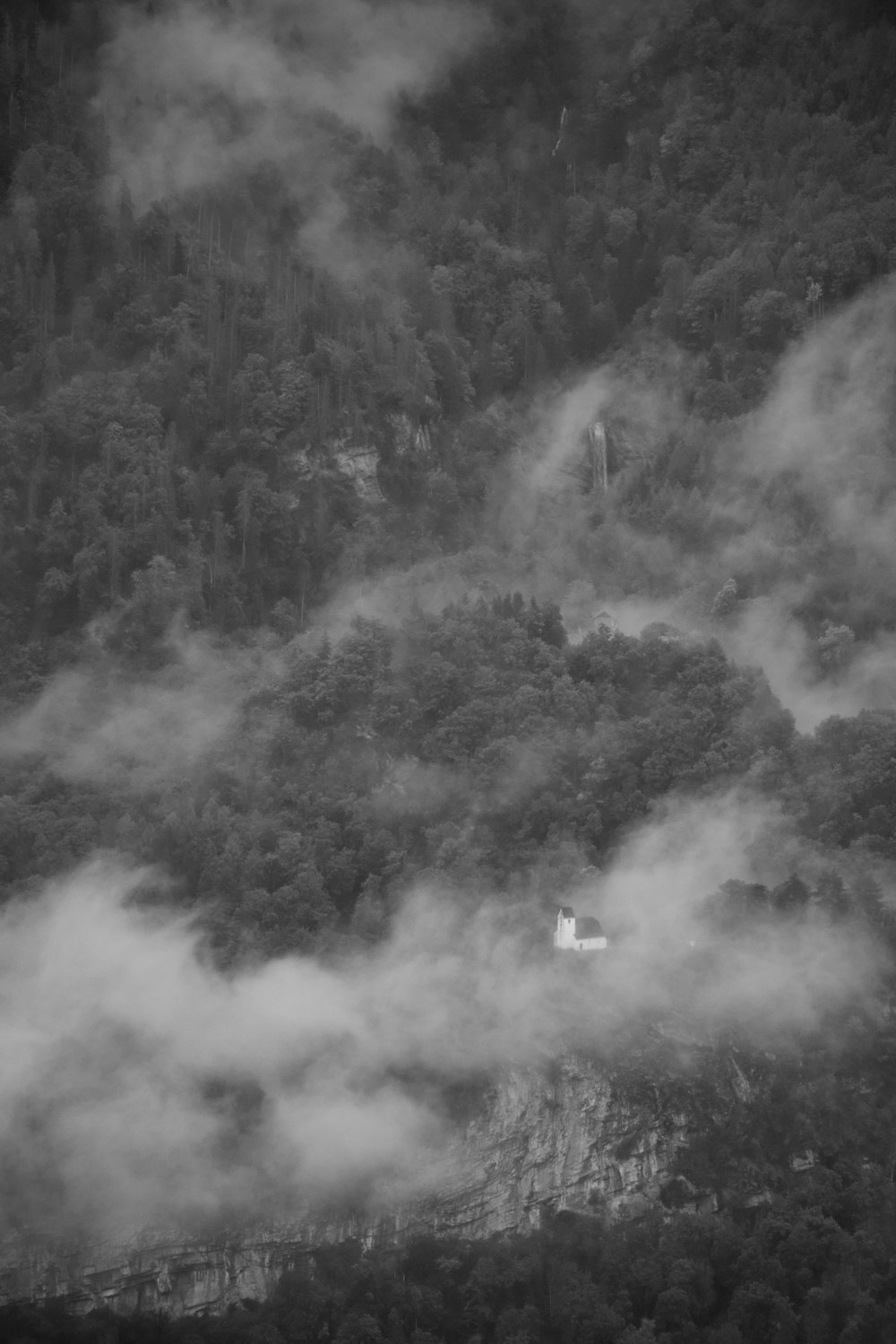 a black and white photo of a mountain covered in clouds