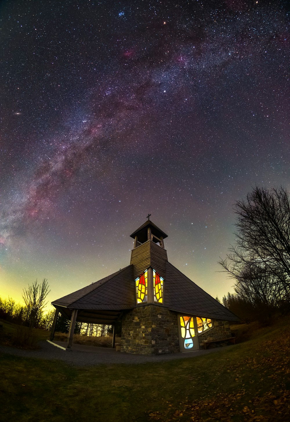 a church with a clock tower under a night sky filled with stars