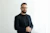a man with a beard and glasses standing in front of a white wall