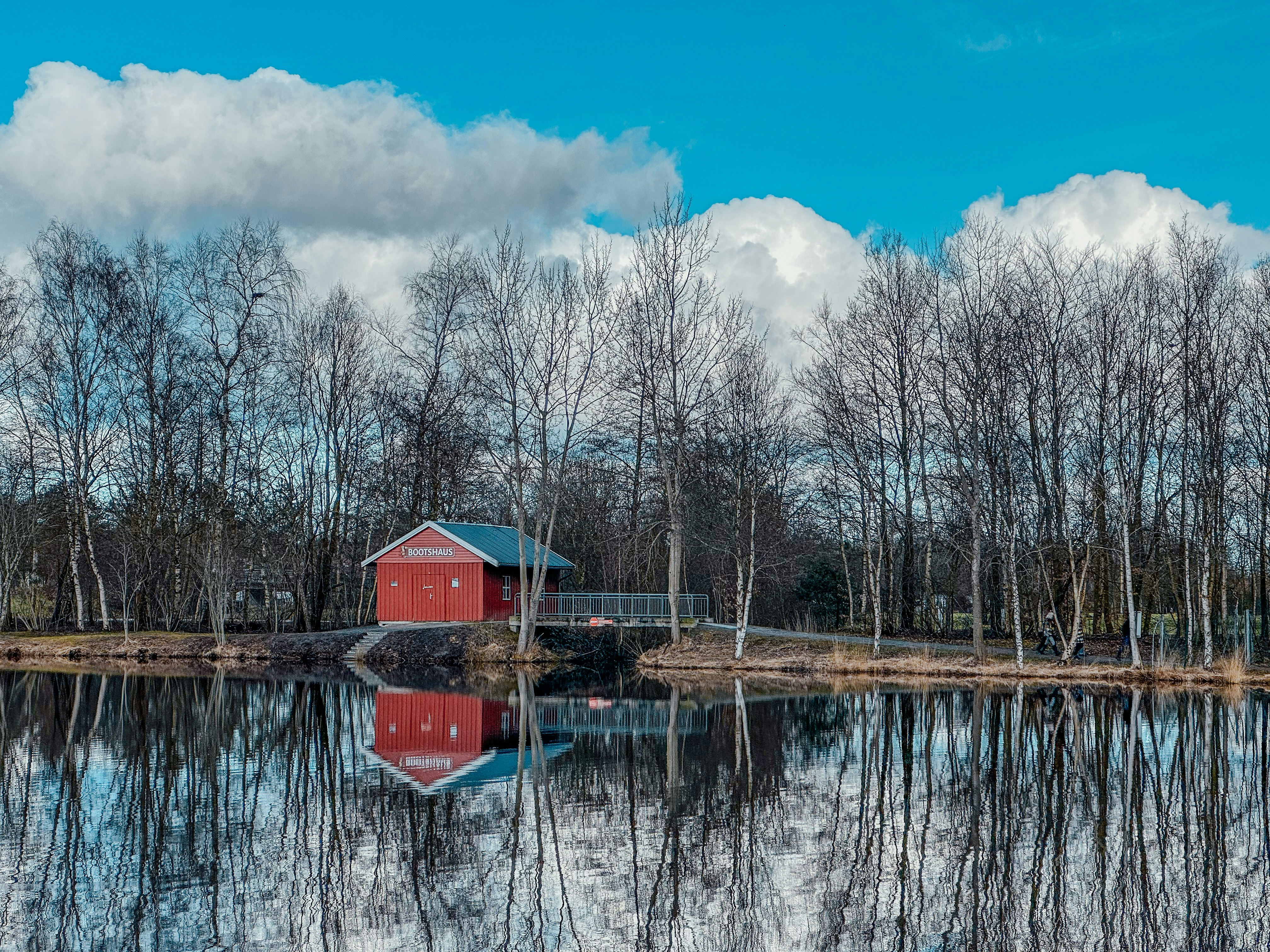 a red house sitting on top of a lake next to a forest