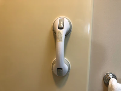 A friendly technician gently installing a grab bar in a senior's bathroom.