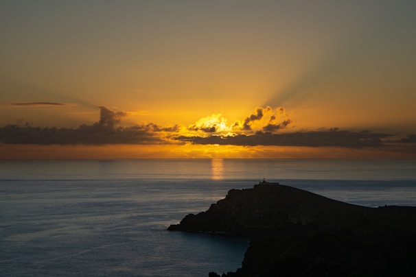 the sun is setting over the ocean with clouds