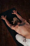 a shirtless man laying on a yoga mat