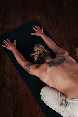 a shirtless man laying on a yoga mat