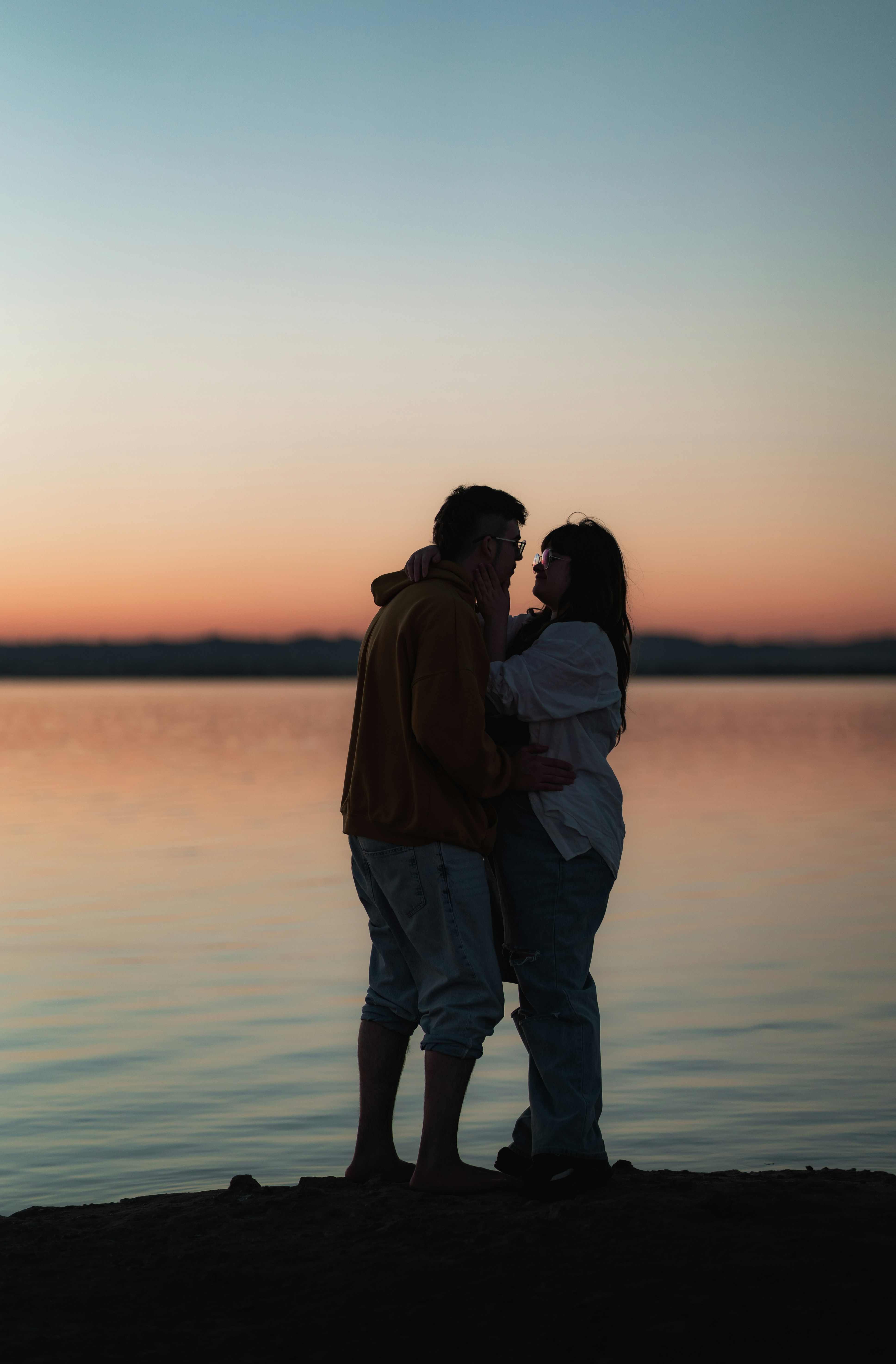 Momen senja romantis pasangan di tepi danau