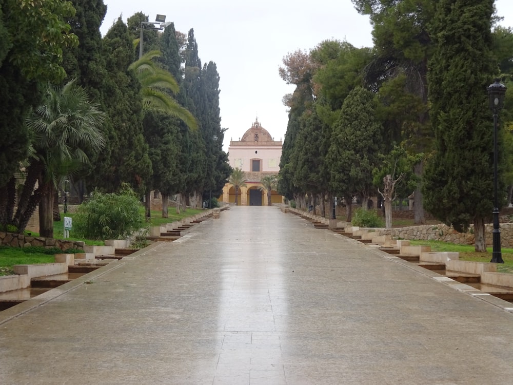 a long road with trees and a building in the background