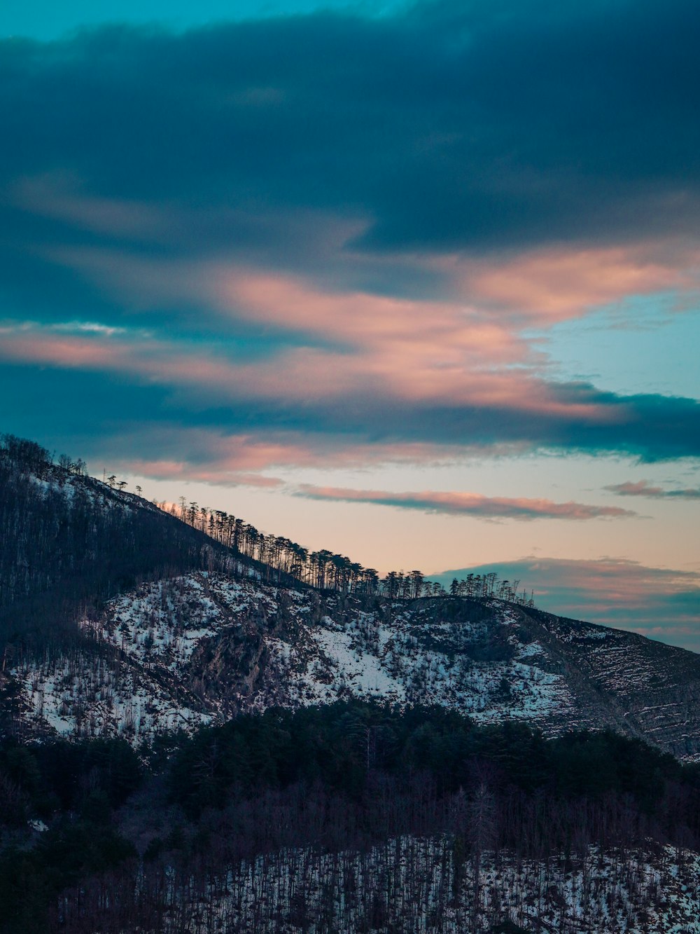 a snow covered mountain under a cloudy sky