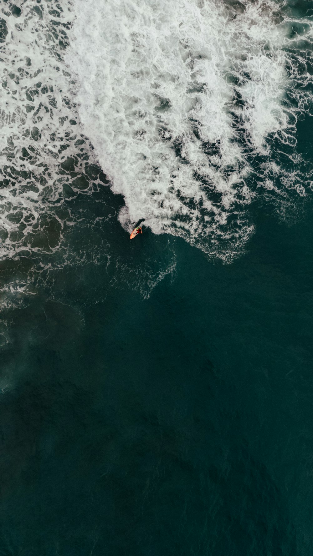 Un hombre montando una tabla de surf encima de una ola en el océano