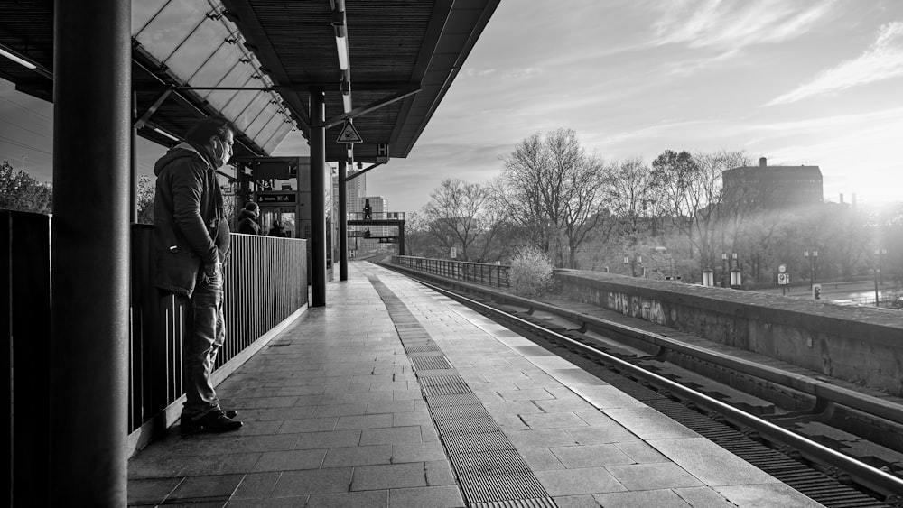 a man standing at a train station waiting for a train