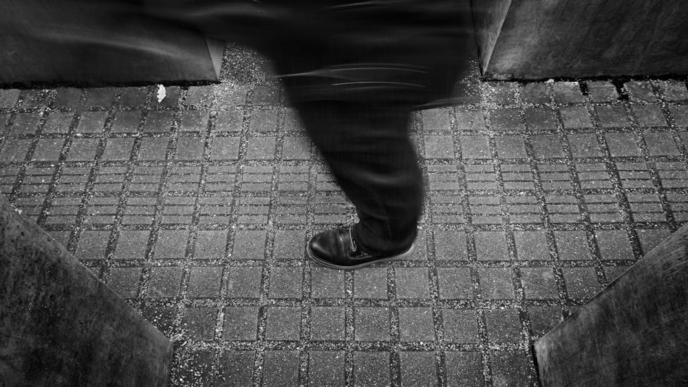 a black and white photo of a person walking down a sidewalk