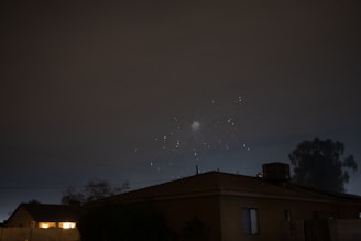 A rooftop party at midnight with silhouettes dancing against a city skyline drenched in darkness.