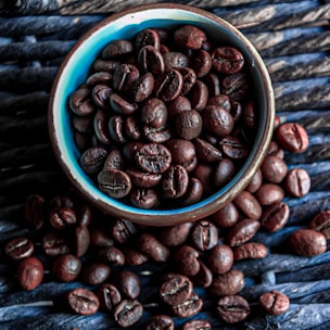 A diverse selection of coffee beans arranged in a rustic wooden bowl.