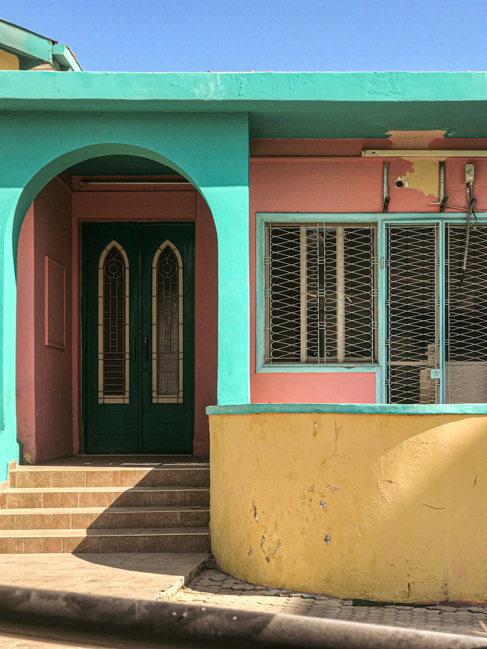 a pink and blue house with a green door
