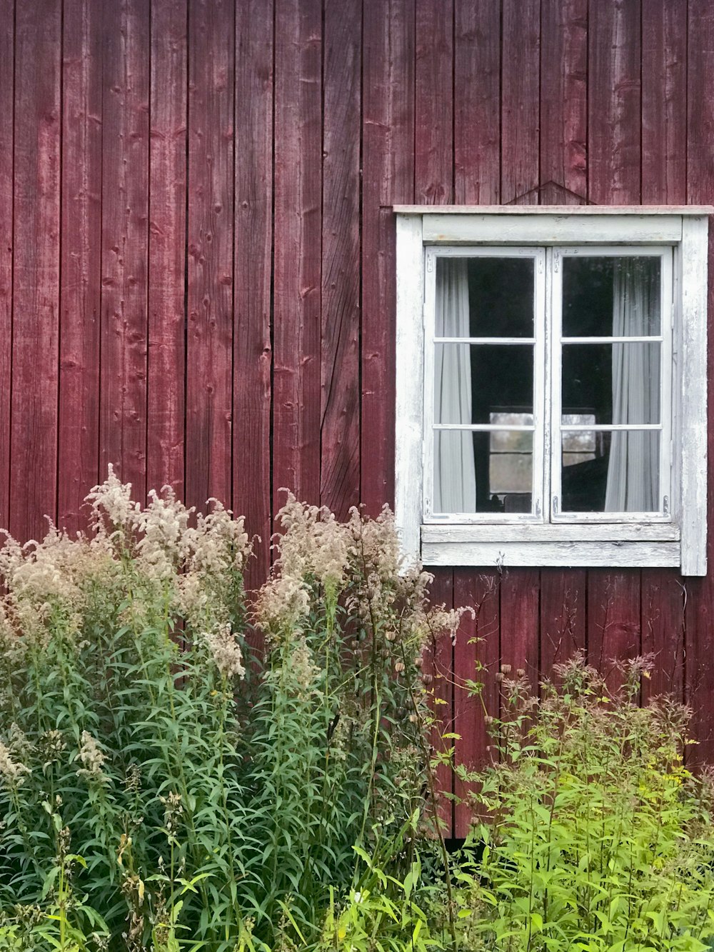 a red building with a window and a chair in the window