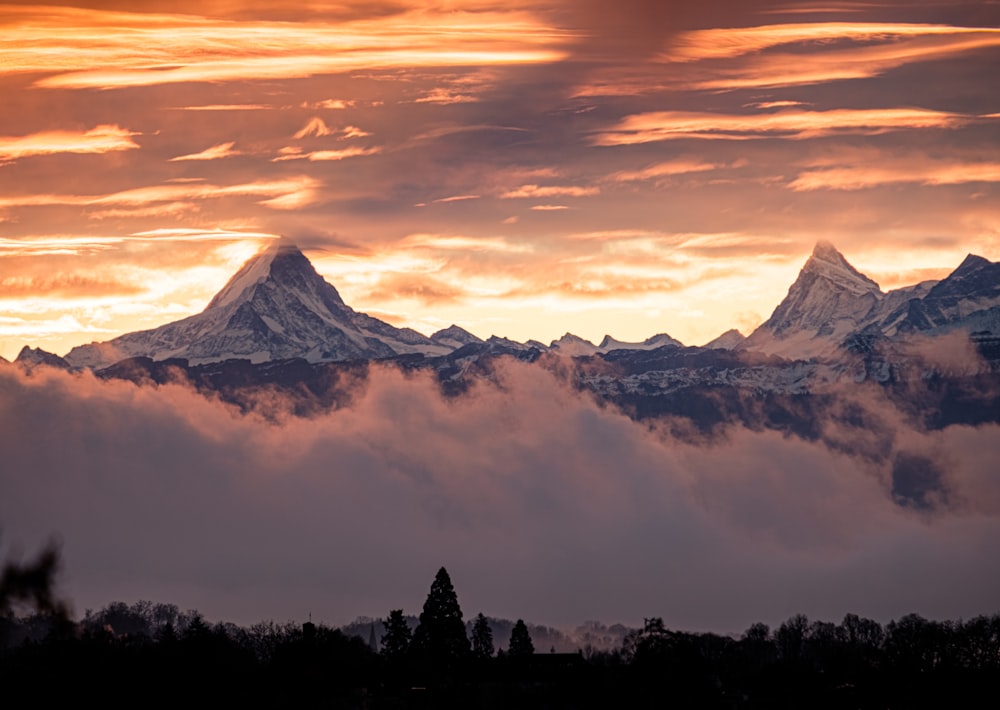 a mountain range covered in clouds at sunset