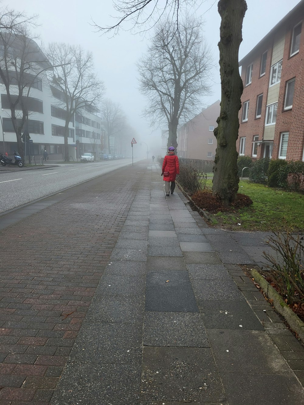 a person walking down a sidewalk in the fog