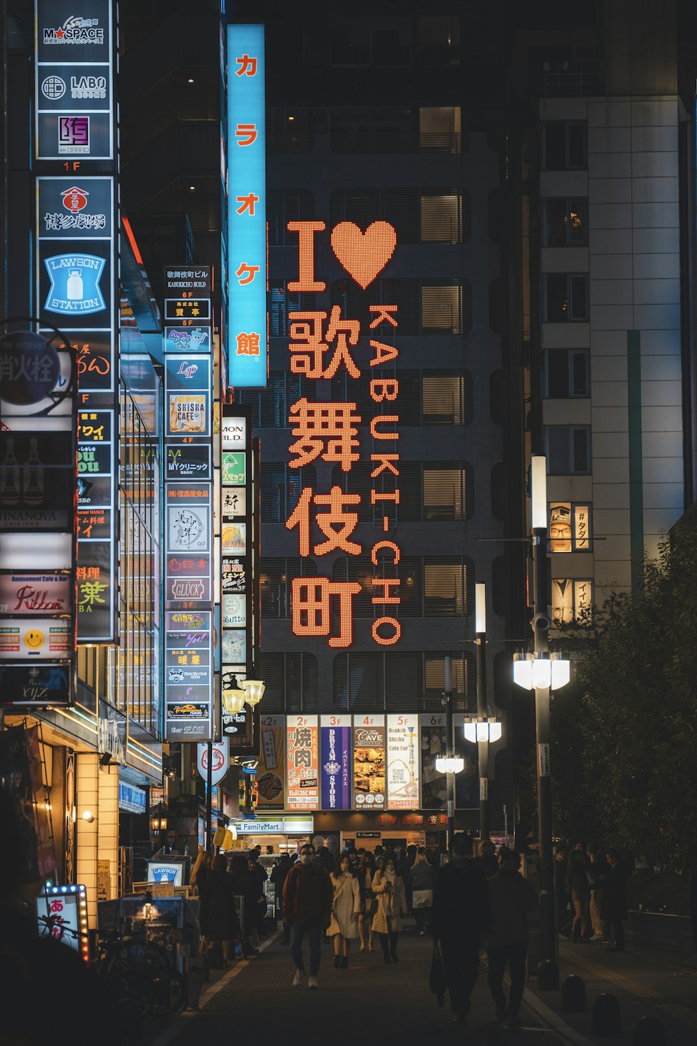 uma rua da cidade à noite com pessoas andando na calçada