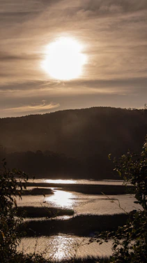 A glowing, colorful digital artwork featuring a peaceful sunrise over a serene landscape with a subtle cross silhouette.