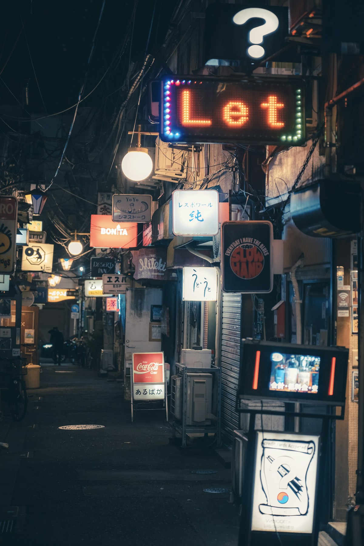 Neon-lit alley in Golden Gai, Shinjuku, lined with tiny bar signs at night