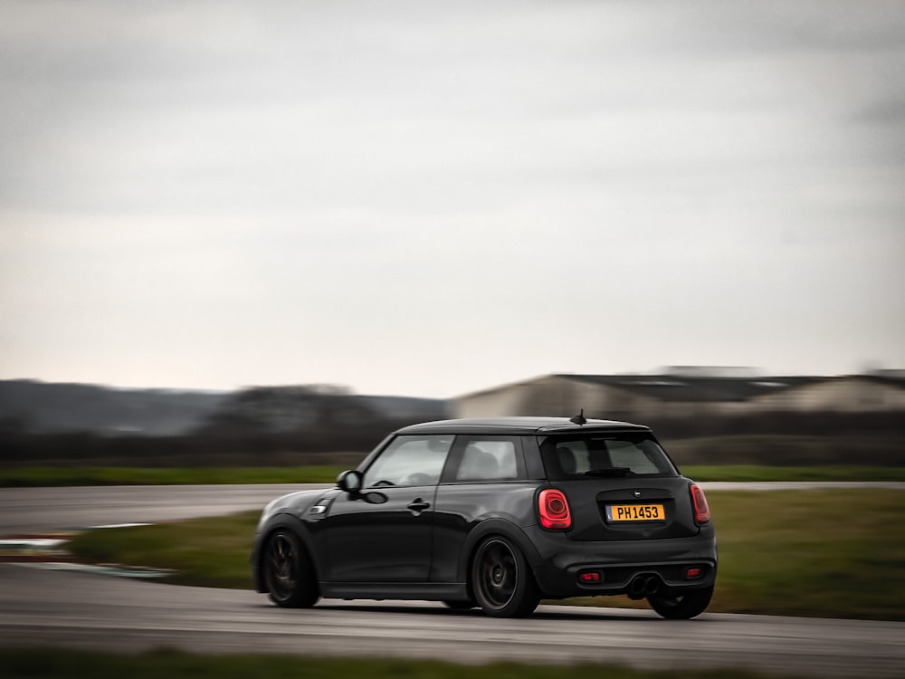 a small black car driving down a road