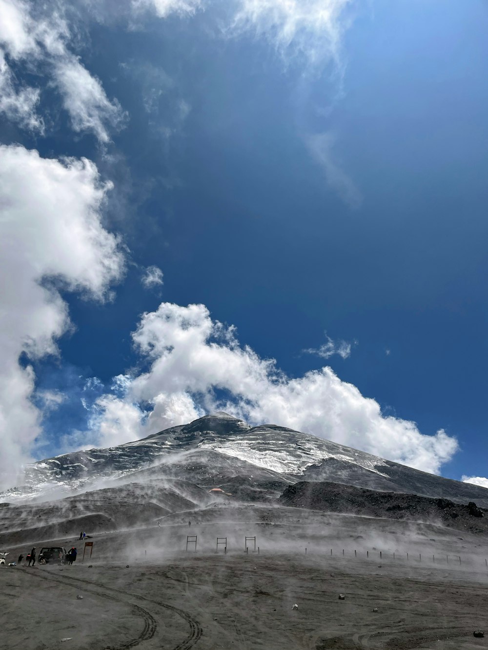 a mountain covered in snow under a cloudy blue sky