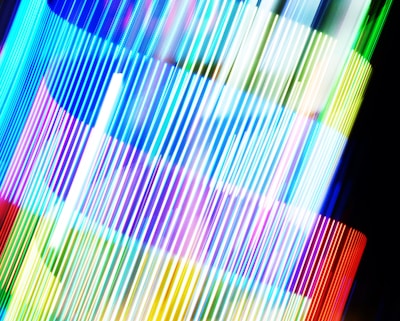 An array of brightly colored vertical lines, possibly created using long exposure photography. The colors blend and overlap, creating a dynamic and vibrant composition.